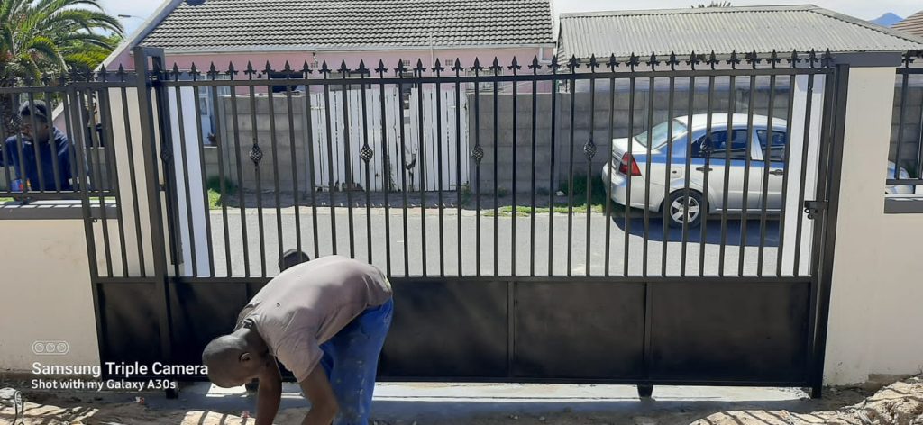 Supar Steel worker making final adjustments to a large driveway security gate installation
