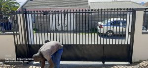 Supar Steel worker making final adjustments to a large driveway security gate installation