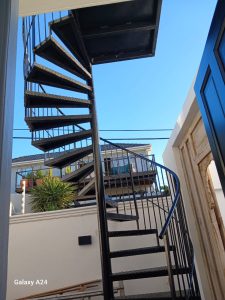 Black steel spiral staircase installed outside a Cape Town home, steel staircase fabrication