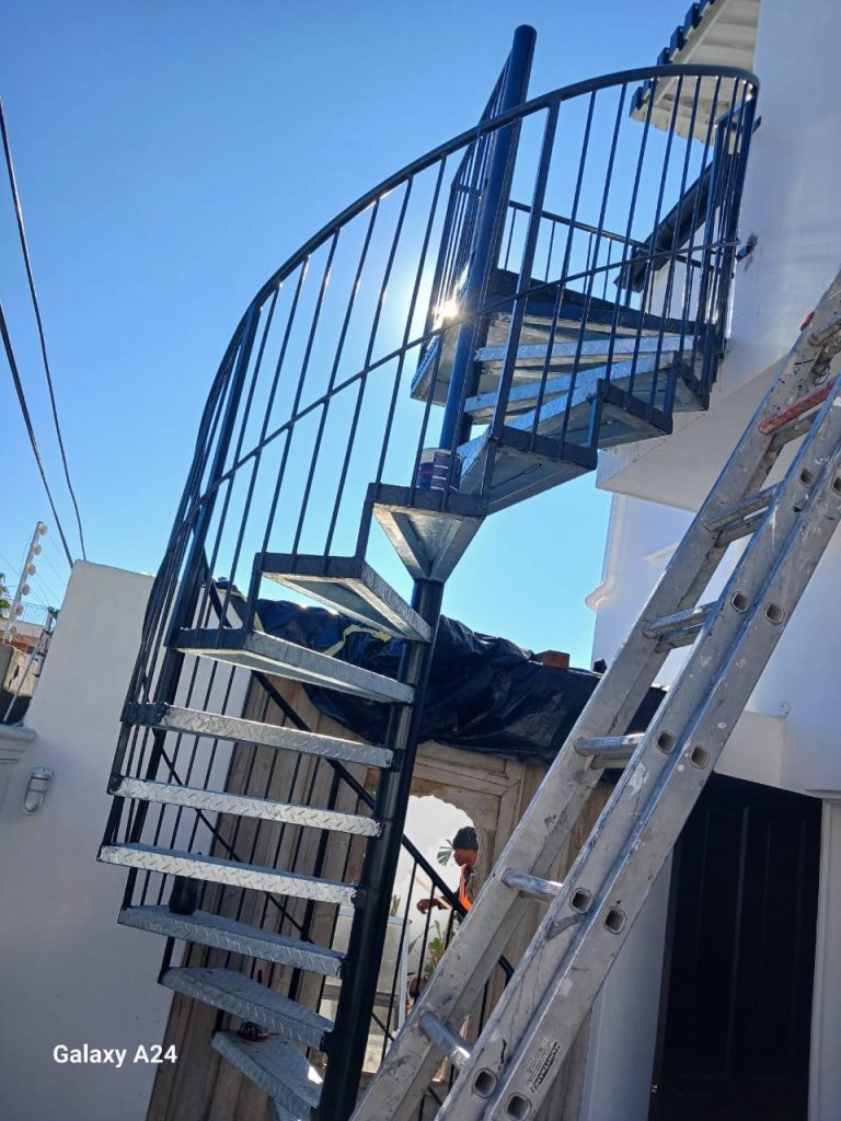Supar Steel technician fitting a steel spiral staircase bracket on scaffolding during on-site installation