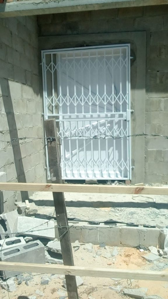 White expandable steel trellis security gate being installed on a house under construction in Cape Town